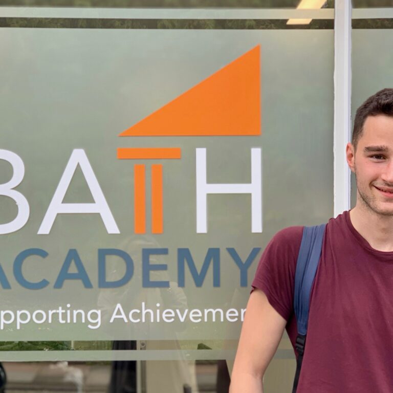 student in front of Bath Academy sign