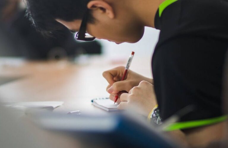 student writing on a notepad